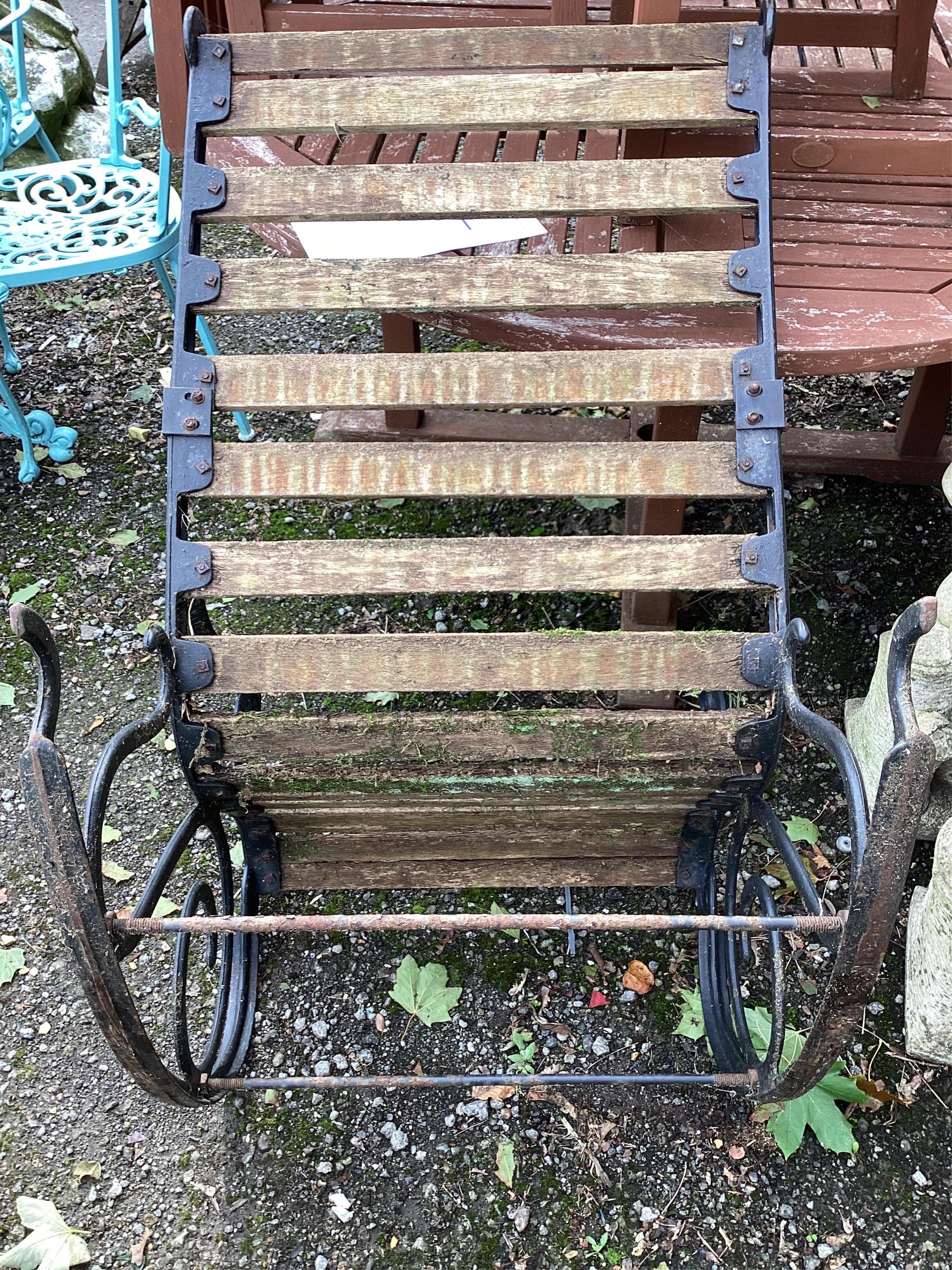 A pair of slatted cast metal garden rocking chairs